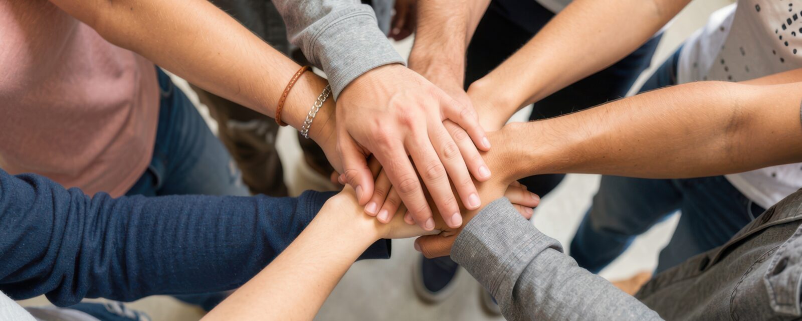 7 handen van verschillende personen op elkaar